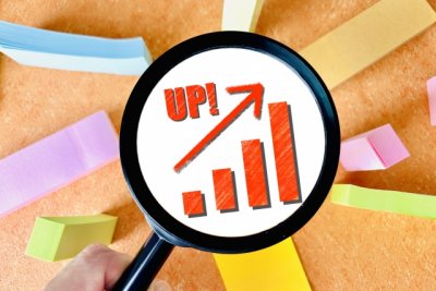 付箋をバックに虫眼鏡の中にUPと右上がりグラフ